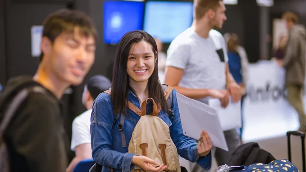 Exchange student holding an envelope, her key and a rucksack on arrival day.