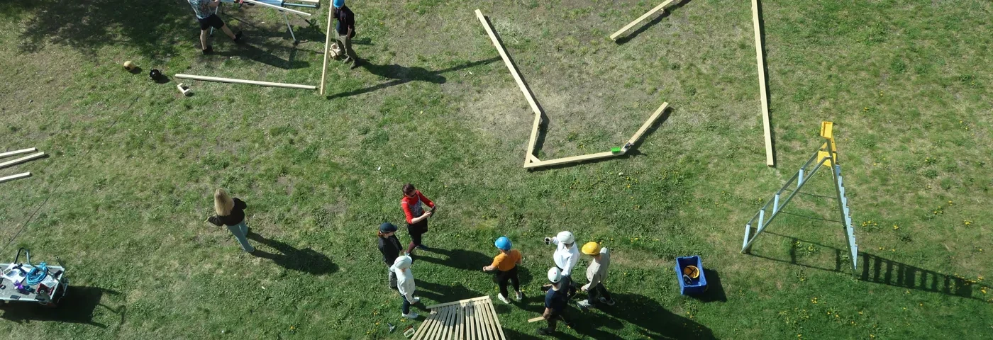 Students working with wood outside on grass