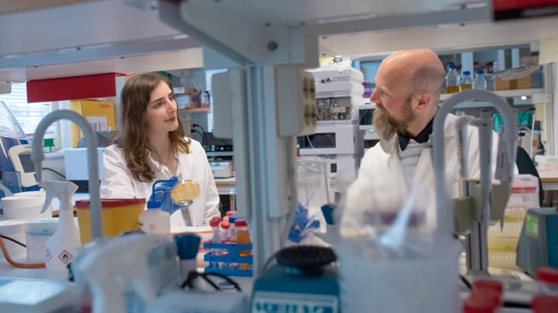 Two people visible through a shelf in a lab.