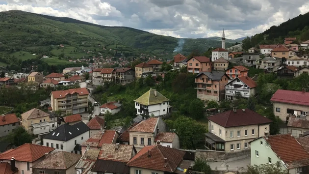 En by med små hus i en dalgång i Bosnien. Skog och berg i bakgrunden.