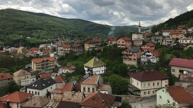 Flertalet små hus i Bosnien, skog och berg i bakgrunden