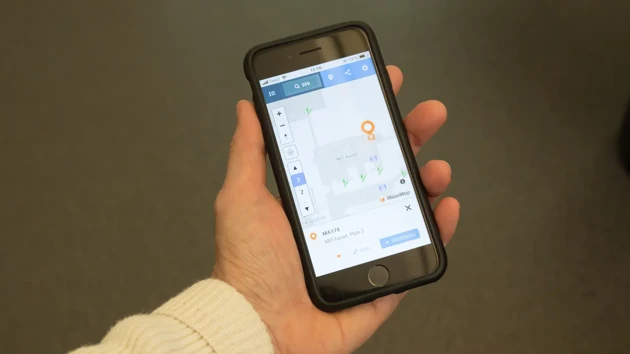 A hand holding a mobile phone showing the online map of campus.