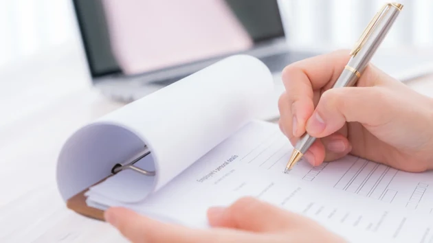 A person writing on a piece of paper with a pen