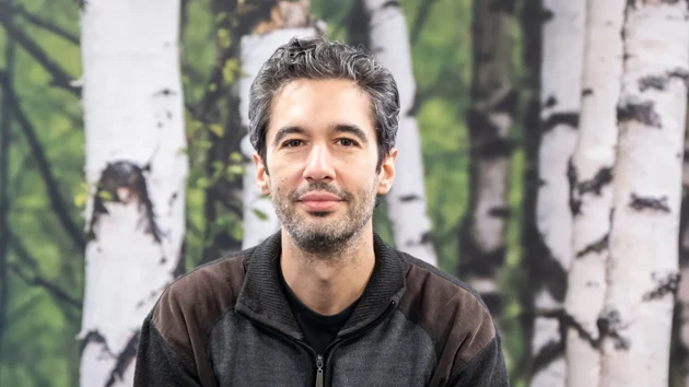 A man standing in front of a painting of trees