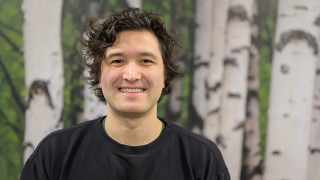 A man standing in front of a painting of trees