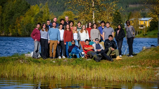 People standing in a fall landscape by a river.