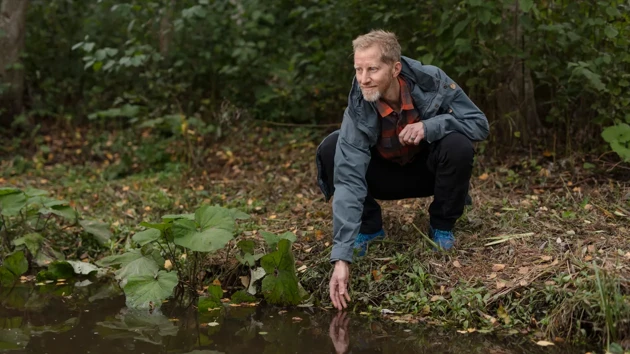 Jan Karlsson puts his hand in a stream