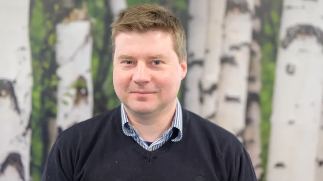 A man standing in front of a painting of trees