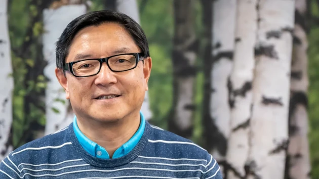 A man wearing glasses standing in front of a painting