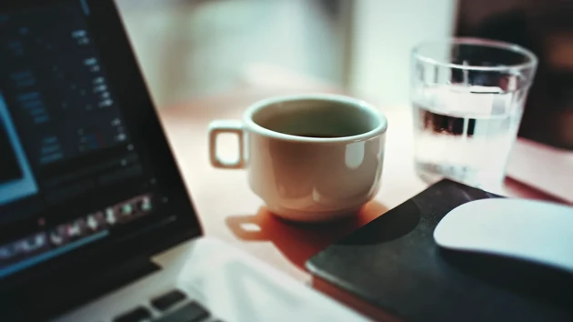 A picture of a coffee cup, a glass of water and a laptop.