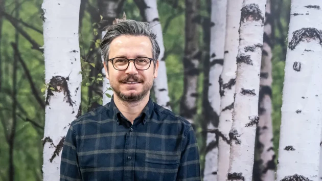 A man standing in front of a painting of trees