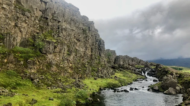 Bild på grönt landskap med berg på Island.