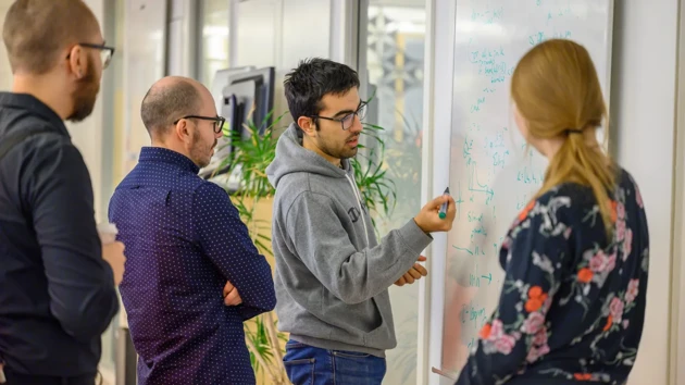 A group of people standing around a white board