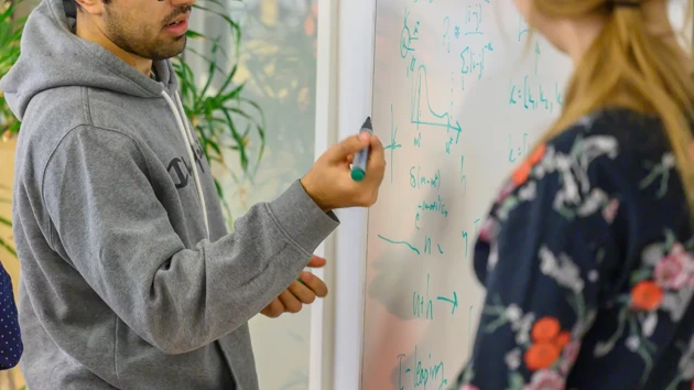 A group of people standing around a white board