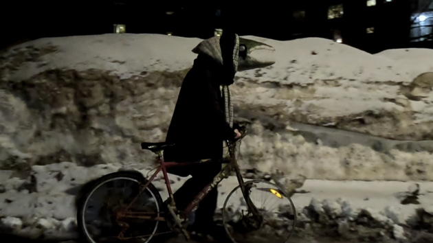 Person med fiskhuvud leder en cykel