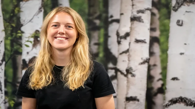 A woman standing in front of a group of trees