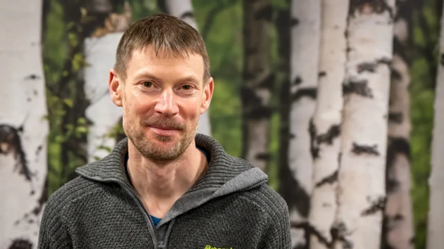 A man standing in front of a painting of trees