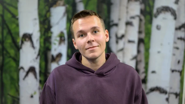 A man standing in front of a painting of trees