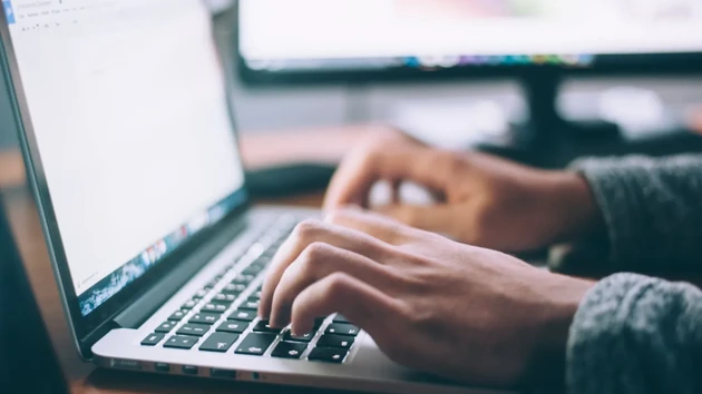 A pair of hands typing on a laptop.