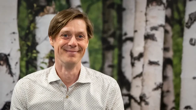 A man standing in front of a painting of trees