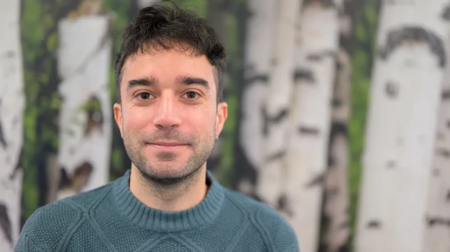 A man standing in front of a painting of birch trees