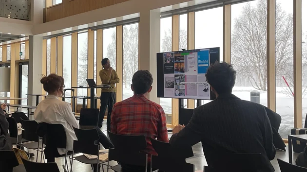 Presentation med publik i Arkitekthögskolans teater, fönster med snö utanför i bakgrund