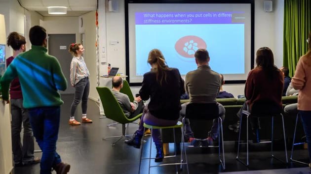 A group of people standing in front of a projector screen