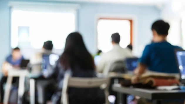 Blurry people sitting in a classroom listening to a lecture.