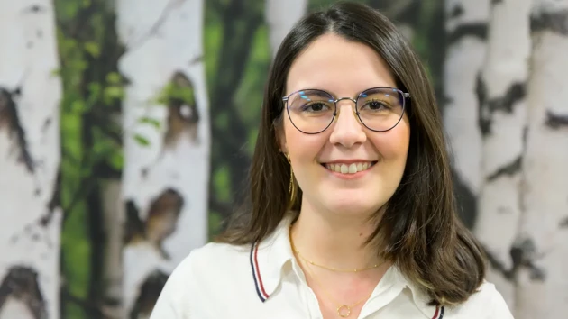 A woman photographed against a backdrop of white birches