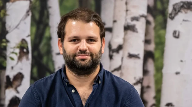 A man standing in front of a painting of trees