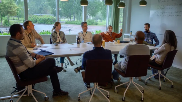 A group of researchers at a table talk together. 