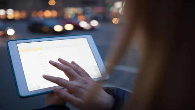 Hand touching a tablet screen.