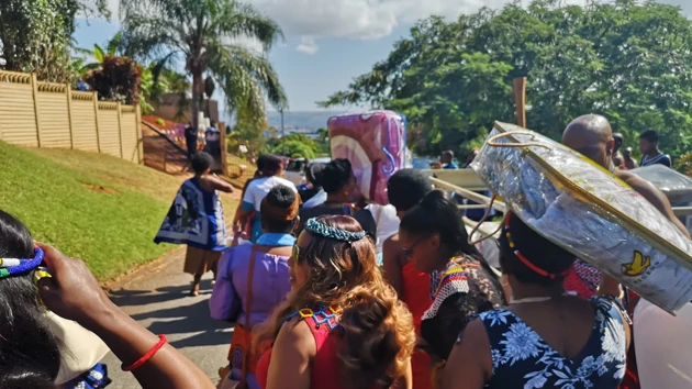 Colourful women walk in a sunny environment with palm trees.