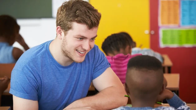 Volontärarbetare hjälper en pojke i en sydafrikansk skolklass på lågstadiet.