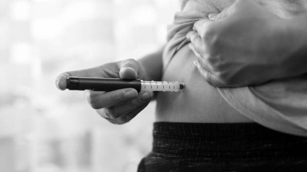 Person som använder en insulinpenna mot magen